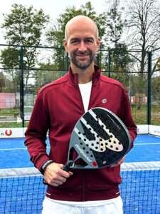 Padel coach Kay Haderer holding a padel racket on an outdoor padel court