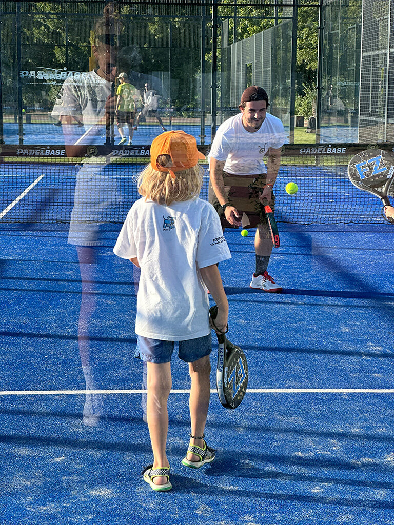 Trainer spielt mit Kindern auf einem Padelplatz der Marswiese in Wien.
